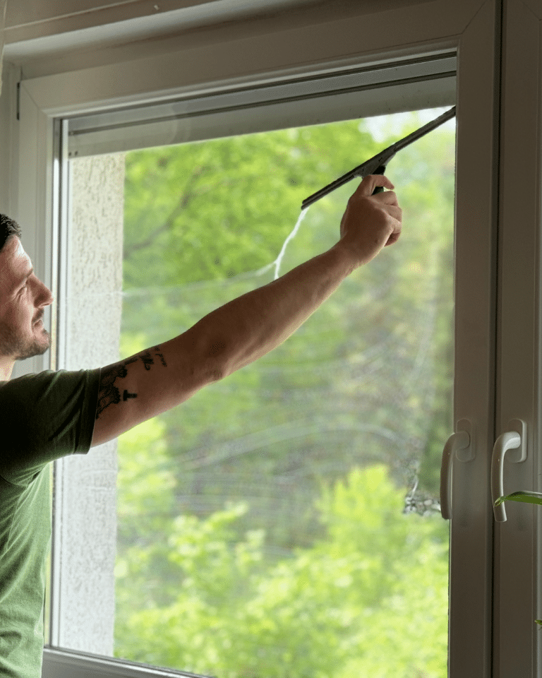 Fensterreinigung – Mitarbeiter säubert eine große Glasscheibe mit professionellem Werkzeug.